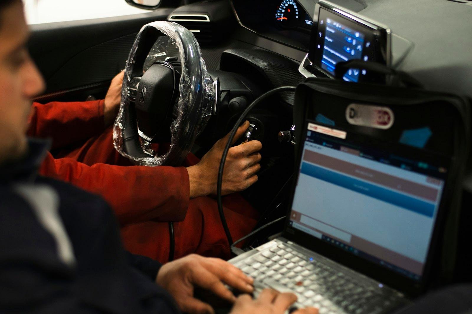Laptop mit Diagnosesoftware auf dem Fahrersitz eines Autos