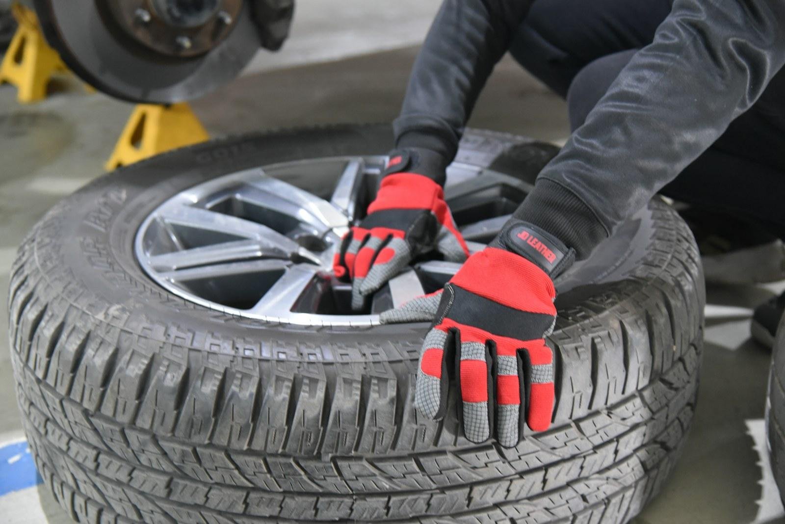 Hände in Arbeitshandschuhen an einem Autoreifen